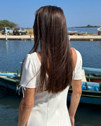 Rochie albă scurtă cloș cu mâneci, elegantă și feminină, lângă apă.