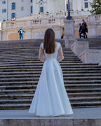 Rochie de mireasa albă lungă din satin elegantă cu șliț și mâneci transparente.