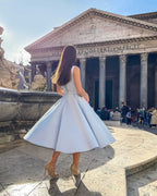 Rochie eleganta midi bleu, fără mâneci, cu șliț și decolteu, din satin regal în fața unui monument.