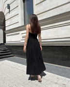 Rochie neagra cu bretele si slit pe picior, vazuta din spate, model in picioare.